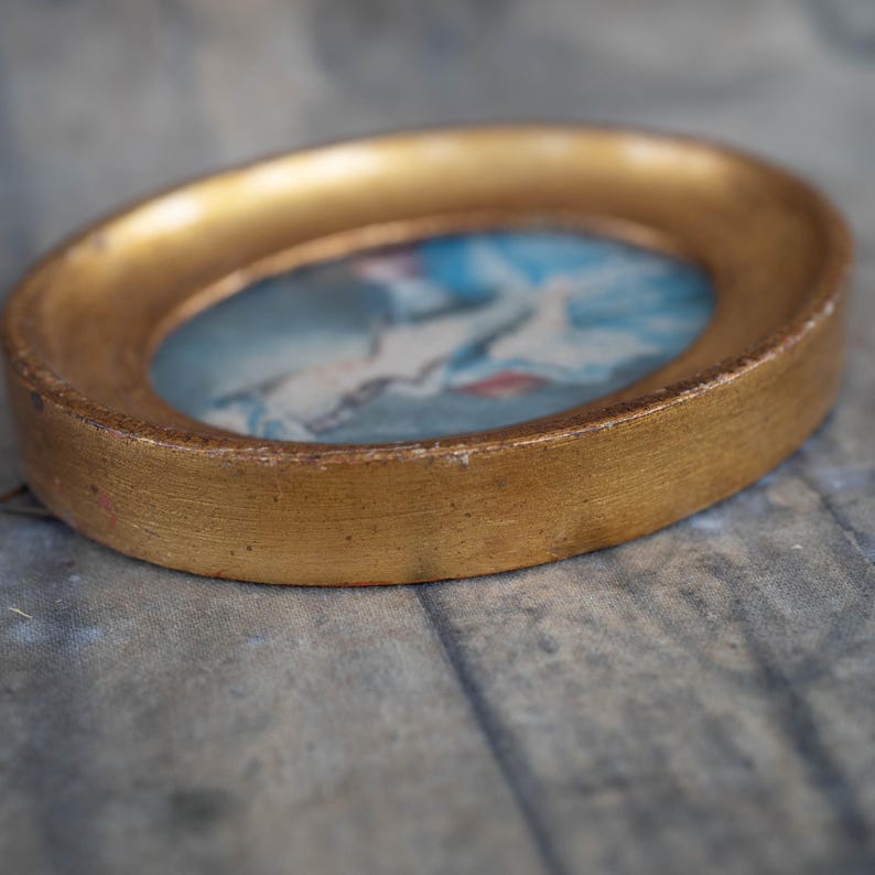 A lower-angle perspective showing the thickness and texture of the miniature oval frame resting on a surface.