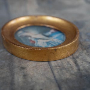 A close-up angled view highlighting the profile and depth of the oval gold frame.