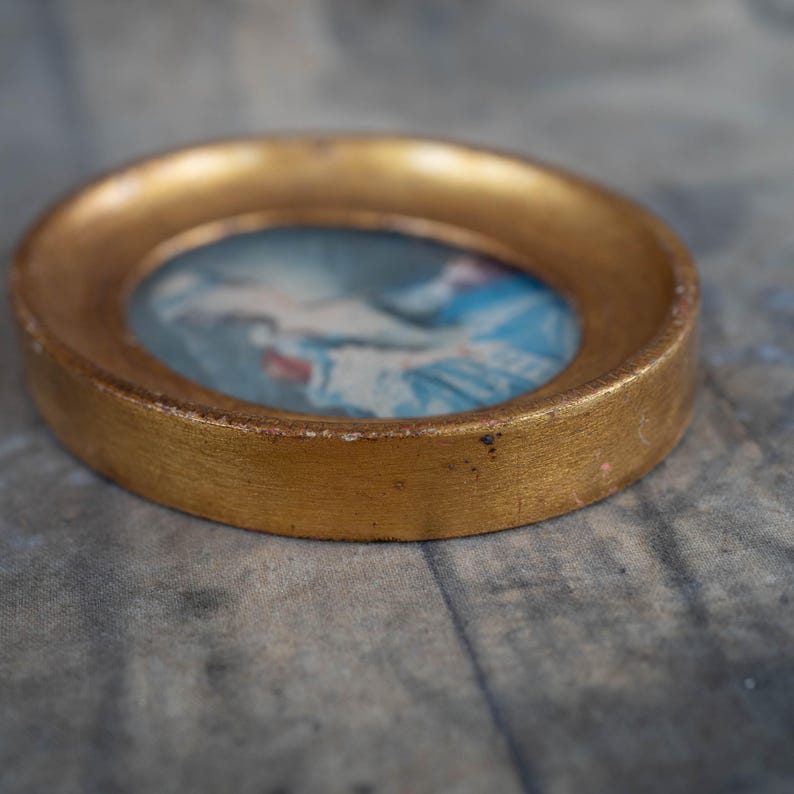 A close-up angled view highlighting the profile and depth of the oval gold frame.