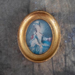 An oval-framed vintage miniature portrait featuring a woman in historical attire.