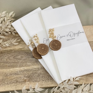 May include: Three white envelopes with gold wax seals and dried flowers. The top envelope has the text "Esra & &Ouml;zg&uuml;rhan Afiyet olsun."