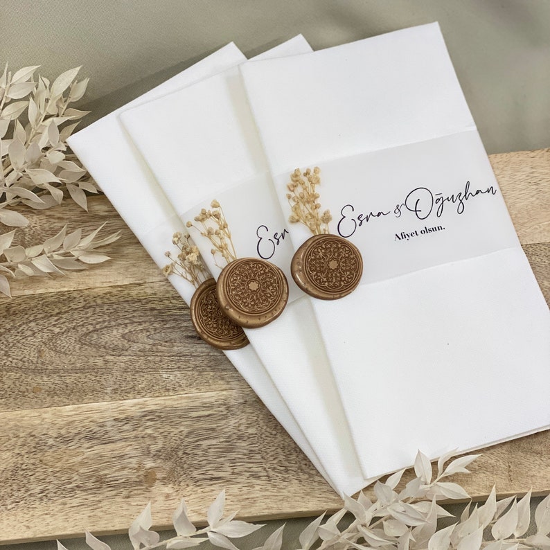 May include: Three white envelopes with gold wax seals and dried flowers. The top envelope has the text "Esra & &Ouml;zg&uuml;rhan Afiyet olsun."