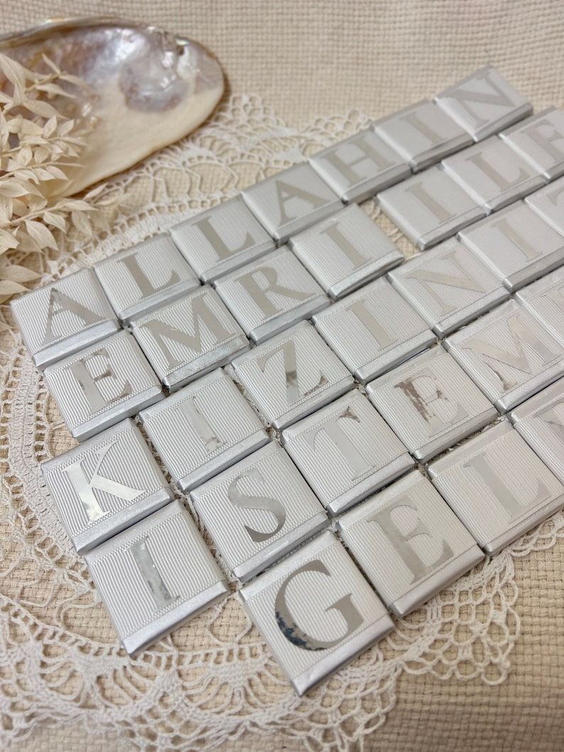 May include: Silver foil-wrapped chocolate squares with letters spelling out the phrase "ALLAHIN EMRINI KIZILIN ISTENEN GELIN"