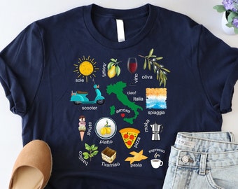 May include: A navy blue t-shirt with a graphic of Italy featuring various Italian icons, including a scooter, pizza, pasta, and espresso. The graphic is surrounded by text in Italian, including "sole", "scoter", "pasta", and "espresso".