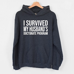 I Survived My Husband’s Doctorate Program Hoodie, Doctorate Hoodie, PhD Finished Hoodie, Doctoral Student Hoodie, Sarcastic Hoodie For Wife