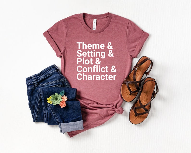 Pu&ograve; includere: Una maglietta color malva con il testo "Theme & Setting & Plot & Conflict & Character" in lettere bianche.
