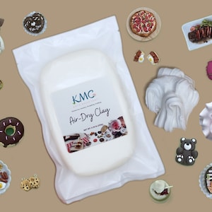 May include: A white package of KMC Air-Dry Clay, a modeling clay that dries in the air. The package is surrounded by miniature food items made from clay, including a pizza, a donut, a hamburger, and a plate of breakfast food. The clay is perfect for crafting and creating miniature food items.