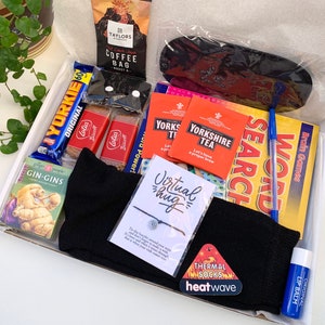 May include: A gift box filled with various items, including a chocolate bar, tea bags, a book, socks, a lip balm, and a bracelet. The box also includes a card that says "Virtual hug".