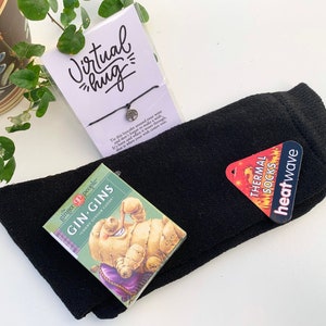 May include: A gift box with a black pair of thermal socks, a small box of ginger candy, and a bracelet with a tree charm. The bracelet has a tag that says "Virtual hug".