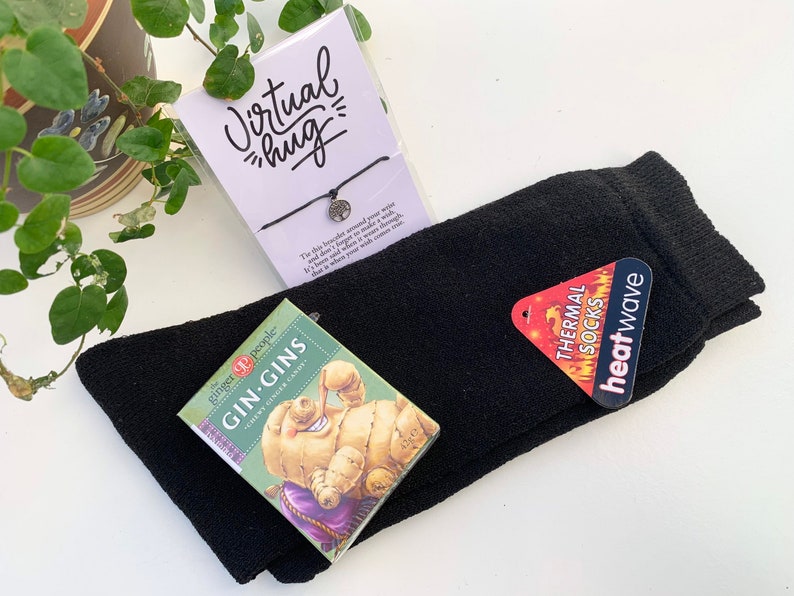 May include: A gift box with a black pair of thermal socks, a small box of ginger candy, and a bracelet with a tree charm. The bracelet has a tag that says "Virtual hug".