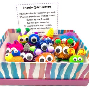 May include: A pink box with a colourful striped pattern contains a collection of fuzzy, colourful creatures with googly eyes. The box has a card on top that reads "Friendly Quiet Critters" and includes a poem about the creatures.