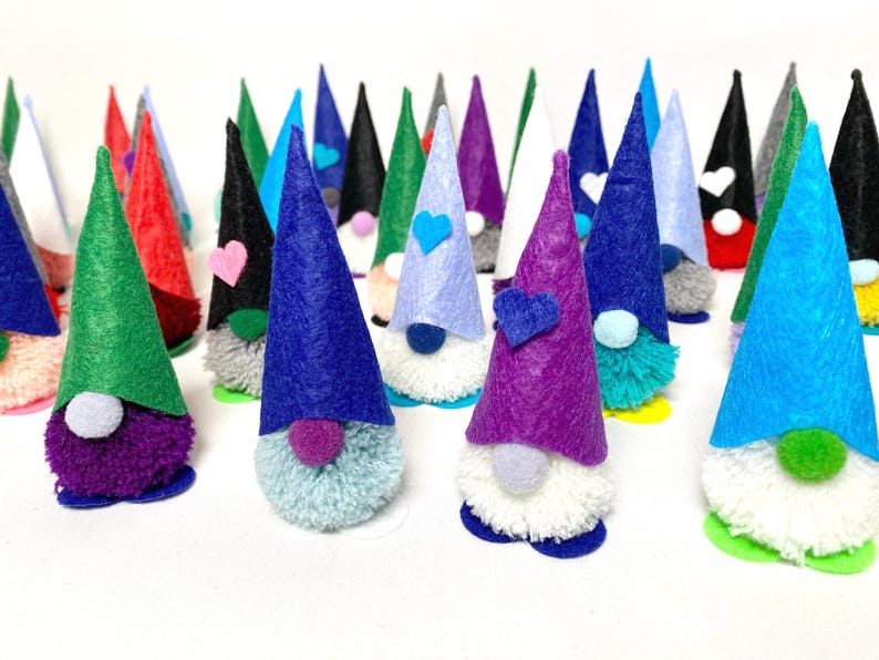 May include: A collection of colorful gnome figurines with felt cone hats in various colors, including blue, green, red, and purple. Each gnome has a fluffy beard and a small pom-pom nose. Some have heart-shaped accents.