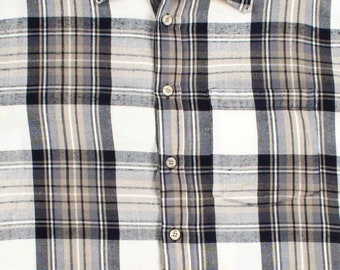 May include: A button-down plaid shirt in a neutral color palette of white, black, and tan. The shirt features a button-down collar, a chest pocket, and the brand name "Arrow Sport" on a tag near the collar.