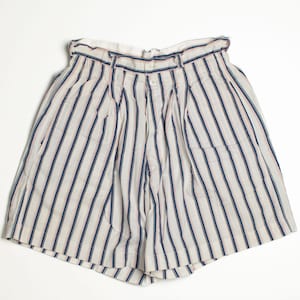 May include: Cream-colored shorts with vertical stripes in navy blue and red. The shorts have a high waist, pleats, and a button closure. The shorts are made of a lightweight fabric.