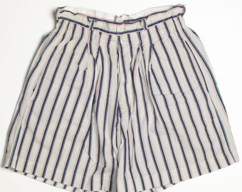 May include: Cream-colored shorts with vertical stripes in navy blue and red. The shorts have a high waist, pleats, and a button closure. The shorts are made of a lightweight fabric.