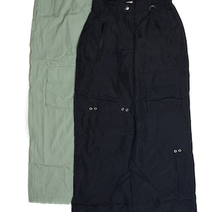 May include: Two pairs of cargo pants, one in a light green color and the other in black. Both pants have multiple pockets and zipper details.