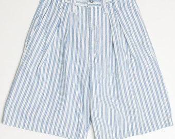 May include: Light blue and white striped shorts with a high waist and pleats. The shorts have a button and zipper closure, and the word "MEMPHIS" is printed on the waistband. The shorts are made of a lightweight fabric.