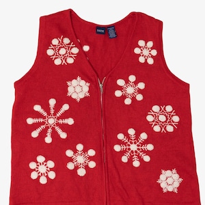 Puede incluir: Chaleco de punto rojo con cuello en V y cremallera completa. El chaleco está decorado con copos de nieve blancos bordados. Una prenda de invierno acogedora.