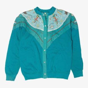 Könnte beinhalten: Türkisfarbenes Sweatshirt mit Knopfleiste und einzigartigem Passe-Design. Die Passe hat einen hellblauen Stoff mit einem vom Südwesten inspirierten Muster in Rot, Braun und Gelb. Das Sweatshirt hat einen runden Kragen und lange Ärmel. Die Knöpfe sind silberfarben.