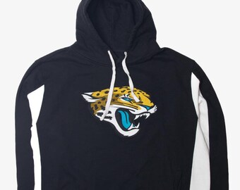 May include: Black hooded sweatshirt with white sleeves and a large embroidered Jacksonville Jaguars logo on the front. The logo features a yellow and black jaguar with a blue tongue.