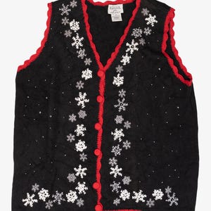 Puede incluir: Chaleco negro sin mangas con ribete y botones rojos. El chaleco está decorado con diseños de copos de nieve blancos y pequeños puntos blancos. Una prenda festiva.