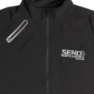 May include: Black athletic jacket with a zippered front and a stand-up collar. Features a zippered chest pocket and the embroidered text "SEND NORTH AMERICA namb.net" in silver. The jacket is designed for outdoor activities.