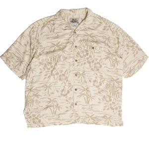 May include: A short-sleeved button-down shirt with a beige background and a repeating pattern of tan palm trees and flowers. The shirt has a collared neckline, a chest pocket, and wooden buttons.