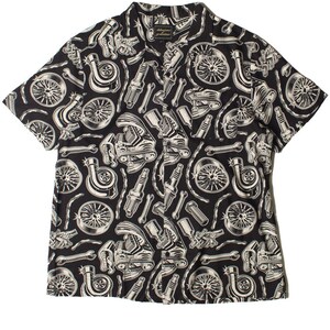 Op de afbeelding: Zwart overhemd met korte mouwen en een patroon van witte auto-onderdelen, waaronder wielen, bougies en turbo's. Het overhemd heeft een kraag. Het is een casual kledingstuk.