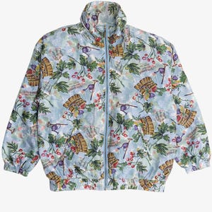 May include: Pale blue zip-up jacket featuring a pattern of grapes, barrels, and gardening tools. The jacket has a high collar and a light blue zip. The design includes green leaves and red berries, giving a vintage feel. The jacket is a casual outerwear item.