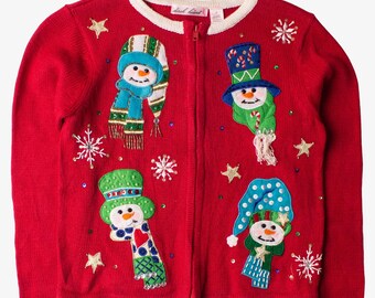 May include: Red zip-up sweater with four snowman appliqués. Each snowman has a different hat and scarf design. The sweater has white trim on the collar and cuffs, with gold star and snowflake accents.