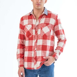 Peut inclure: Une chemise à manches longues à carreaux rouge et blanc avec un col en denim bleu. La chemise a deux poches poitrine et un devant boutonné.