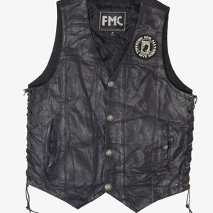 May include: Black leather vest with a V-neck, button closure, and side lacing. Features a patch with the text "SOME GIVE ALL" and the brand "FMC". A classic biker vest.