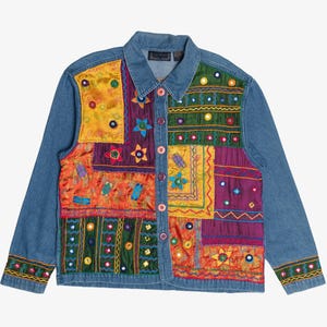 May include: A blue denim jacket featuring a patchwork front panel with vibrant silk-like fabric squares in yellow, orange, green, and purple. The panels are decorated with embroidered star and floral motifs, small circular mirrors, and buttons.