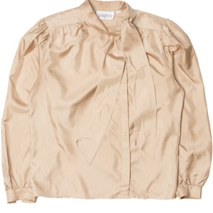 May include: A tan-colored blouse with long sleeves and a high neckline. The blouse features a large bow detail at the neck and the brand name "josephine" on the collar. The fabric has a slight sheen, and the sleeves are gathered at the shoulders.