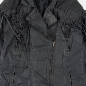 May include: Black leather jacket with fringe detailing on the shoulders and sleeves. The jacket has a zipper closure and multiple pockets. The label on the jacket reads "COMINT".