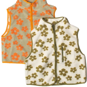 Puede incluir: Dos chalecos de forro polar reversibles con un patrón floral. Un chaleco es verde con flores naranjas, y el otro es blanco con flores verdes.