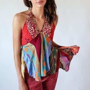 May include: A patchwork halter top in vibrant colors, including red, blue, and purple. The top features a V-neck design and a flowing, asymmetrical hemline. The fabric appears to be a mix of patterned textiles.