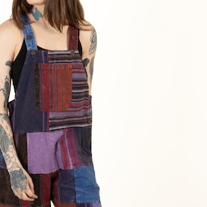 May include: A patchwork overall with a mix of blue, purple, red, and brown fabric. The overall has a relaxed fit and a casual style.