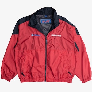 May include: A red and black windbreaker jacket featuring a full-length front zipper, elastic cuffs, and a high collar. The chest displays the Yamaha logo and the text Skeeter, while a blue Sport patch is located on the inner neck area.