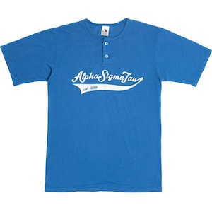 May include: A royal blue short-sleeved t-shirt with a white button-up collar and a white graphic that says "Alpha Sigma Tau est. 1899" in a cursive font.