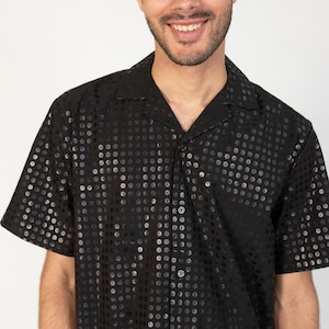 May include: A black short-sleeved button-down shirt with a silver sequin pattern.