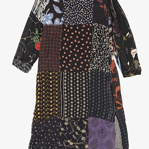 May include: A long patchwork dress featuring a variety of patterned fabrics in black, blue, red, yellow, and purple. The dress has long sleeves and a slit on the side. The dress is made of a lightweight material.