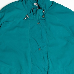 Puede incluir: Chaqueta de color turquesa con cuello alto y cierre de cremallera. La chaqueta tiene un cordón en el cuello y la cintura, y presenta detalles metálicos plateados. La chaqueta tiene una parte delantera abotonada y un estilo clásico e informal.