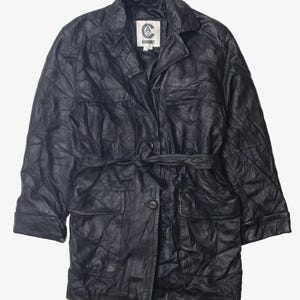 May include: A black leather jacket with a belt, two large pockets, and a smaller pocket on the chest. The jacket has a button closure and a label that reads "COMBAT".