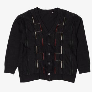 May include: Black cardigan sweater with a V-neck and button closure. The sweater features vertical stripes and geometric patterns with red, green, and white accents. A classic knitwear piece.