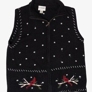 Könnte beinhalten: Schwarze Weste mit Reißverschluss und weißen Schneeflocken- und Nahtdetails. Mit gestickten roten Kardinälen auf Ästen mit grünen Blättern. Ein gemütliches Kleidungsstück zum Thema Winter.