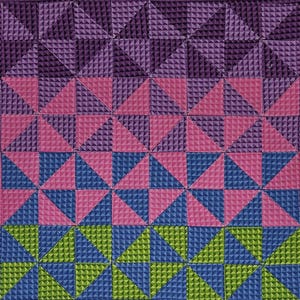 Pode incluir: Uma colcha com um padrão geométrico de triângulos em tons de roxo, rosa, azul e verde. Os triângulos são dispostos em um padrão repetitivo, criando um design visualmente interessante.