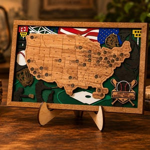 May include: A rectangular wooden framed wall art piece featuring a layered map of the United States with baseball stadium locations. The design includes baseball silhouettes, a glove, a ball, and a plaque reading Hauer Family Baseball Travel Map.