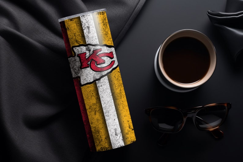 May include: A stainless steel tumbler with a white, red, and yellow design featuring the Kansas City Chiefs logo. The tumbler has a distressed look and is on a black surface.