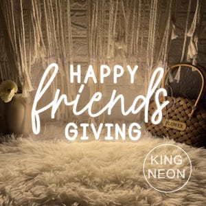 May include: A neon sign with the words "HAPPY FriendsGIVING" in white script. The sign is on a fluffy, cream-colored rug. A woven basket with a "FLOWER" tag and a vase with a flower are in the background. The sign also has the text "KING NEON".
